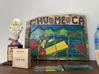 La Chumeca coffee display, colorful painted sign and "Drink Coffee and be Good" box
